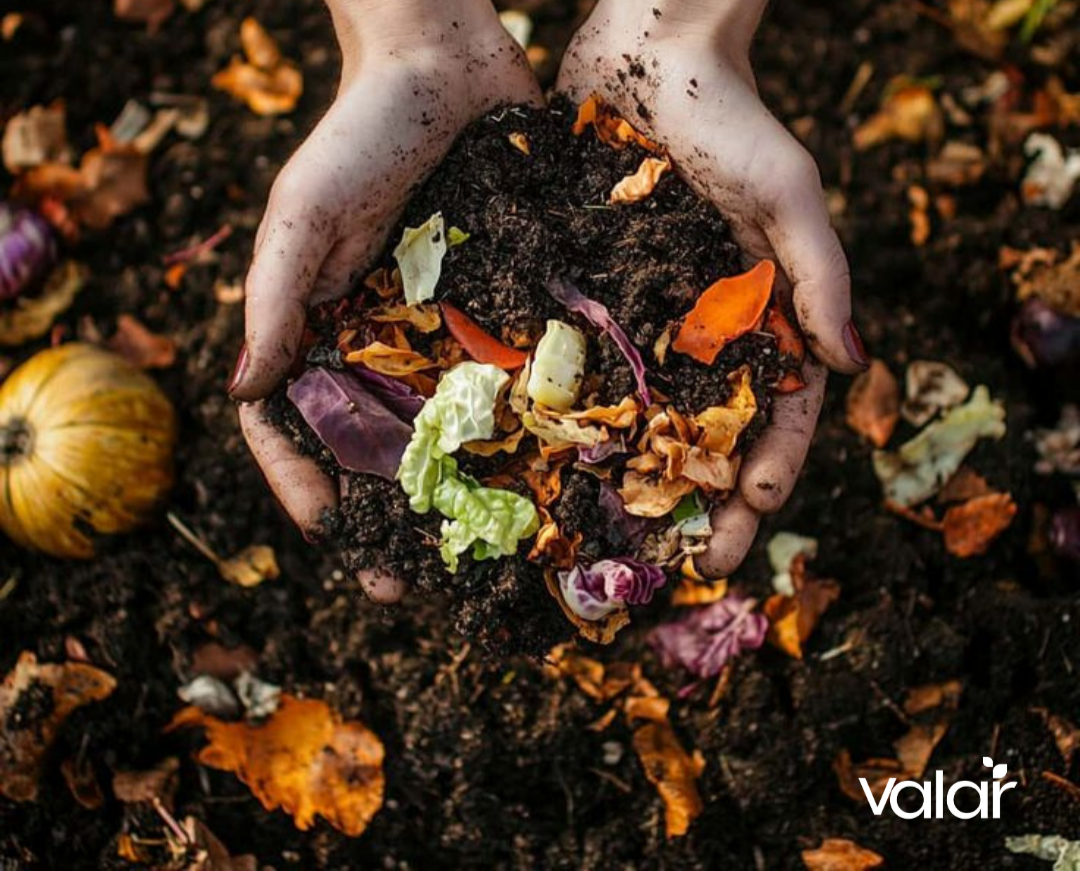 Hands holding compost with food waste, surrounded by compostable materials on a dark background.